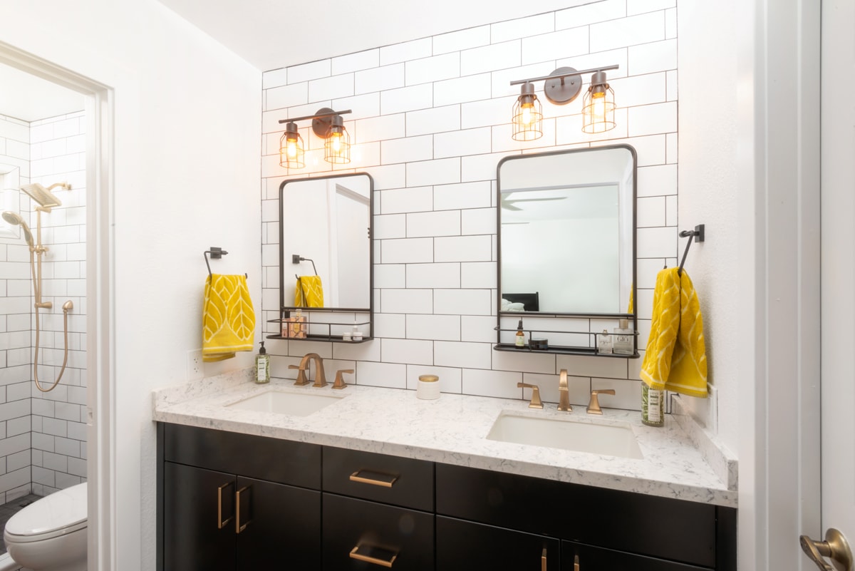 Dark brown double bathroom vanity with subway tile backsplash and gold hardware.