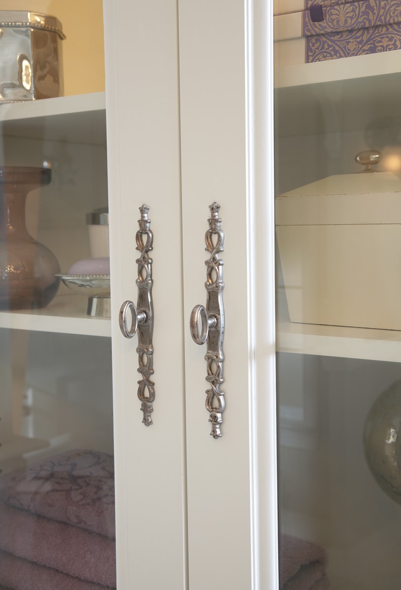 White china cabinet with ornate chrome hardware.