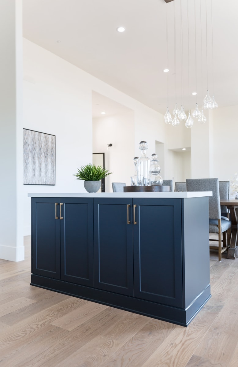 Navy blue island in a home with white walls and distressed flooring.